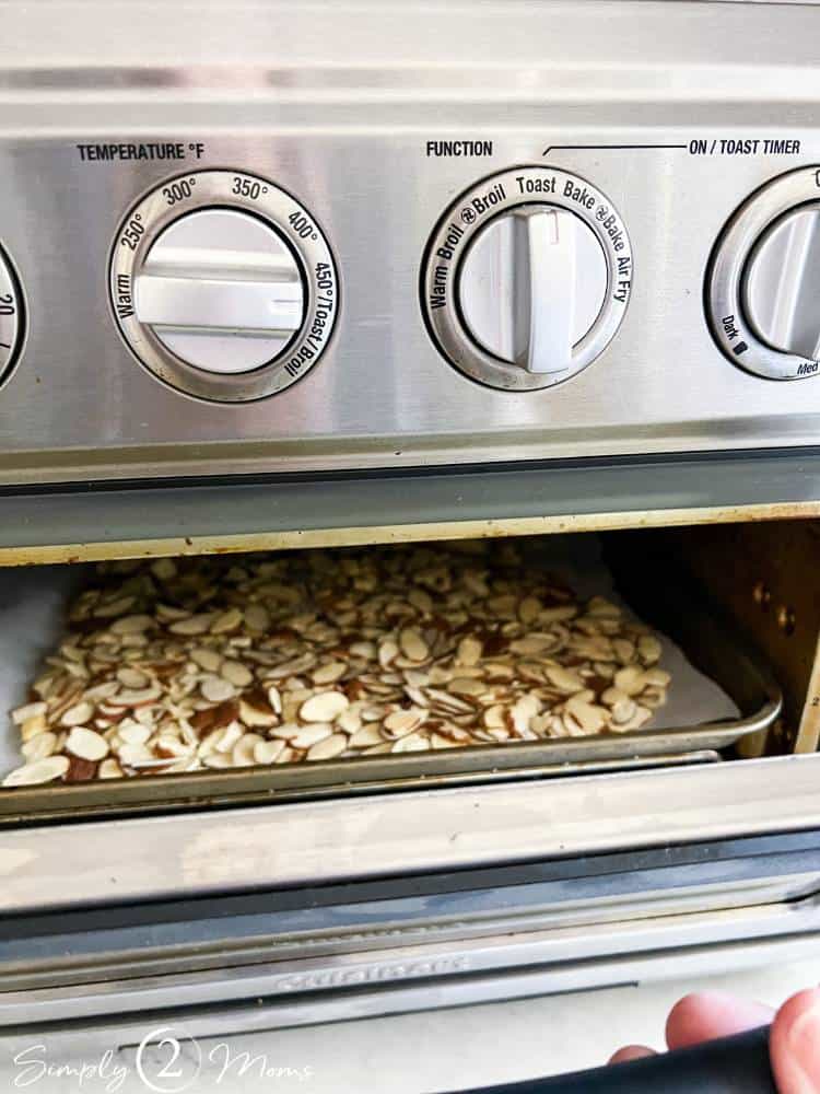 Tabletop air fryer toaster oven combo with a tray of sliced almonds inside.