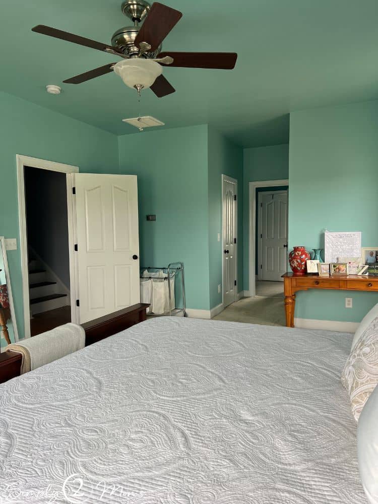 Master bedroom with turquoise ceiling and walls, cherry furniture, white curtains, and ceiling fan.