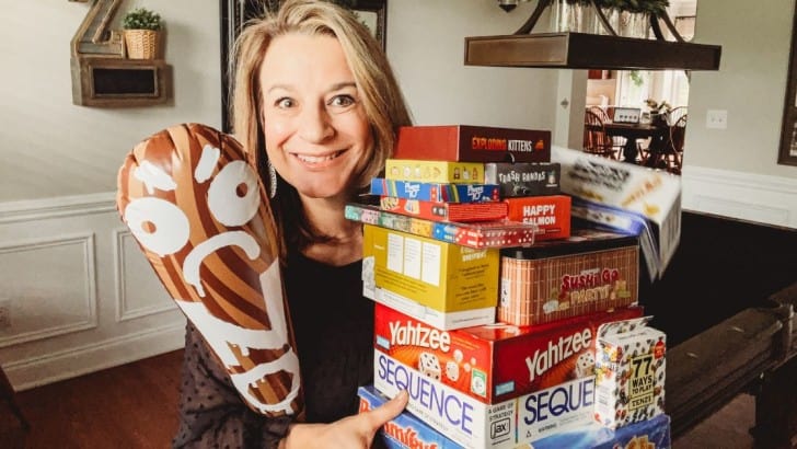 Anne from Simply2Moms holding their favorite games for game night with friends and young adults.