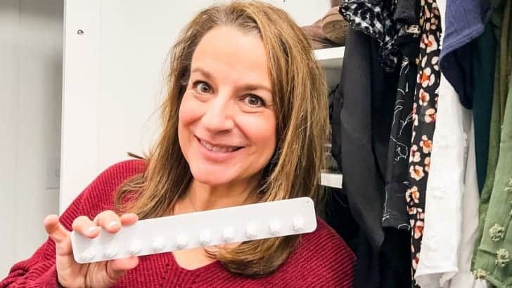 Woman holding an adhesive plastic necklace organizer inside a closet.