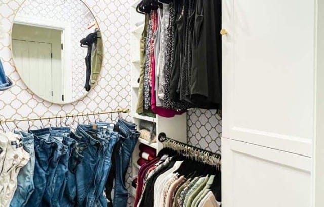 Small walk-in closet with Billy bookcases to hold hanging rods on the sides and a bar to hang jeans on the back wall.
