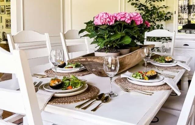 White dining table with deep pink hydrangeas in a trencher bowl with baked avocados on the platesfor Mother's Day luncheon.