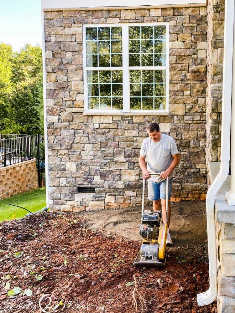 man using compactor on crush and run gravel near house