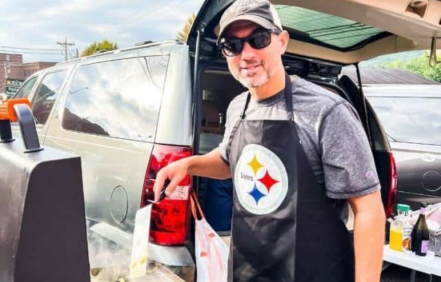 man cooking eggs and bacon on Blackstone while tailgating