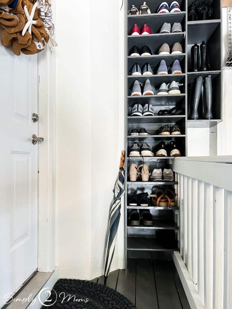 DIY shoe shelves built in on a wall in a garage landing next to the entrance door for the house.