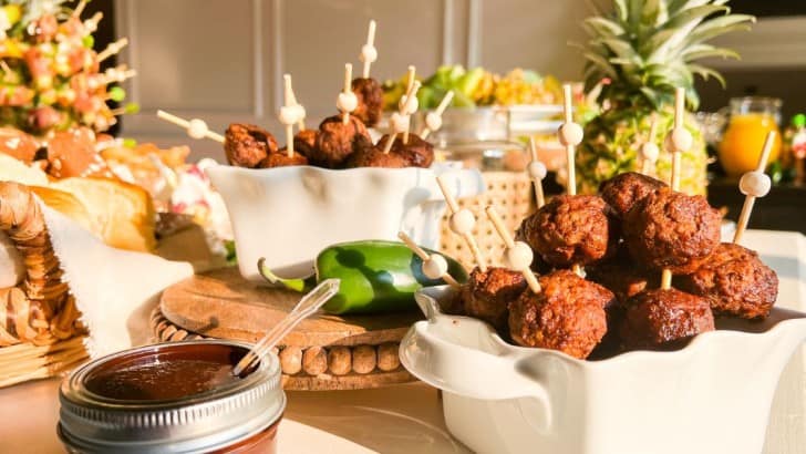 Table set for a tropical cocktail party with jerk meatballs and pineapples.