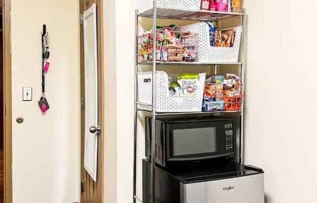 corner of room styled with shelf system over mini fridge and microwave