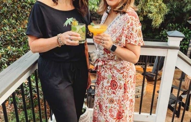 AnnMarie and Anne standing on deck outside holding tropical cocktails