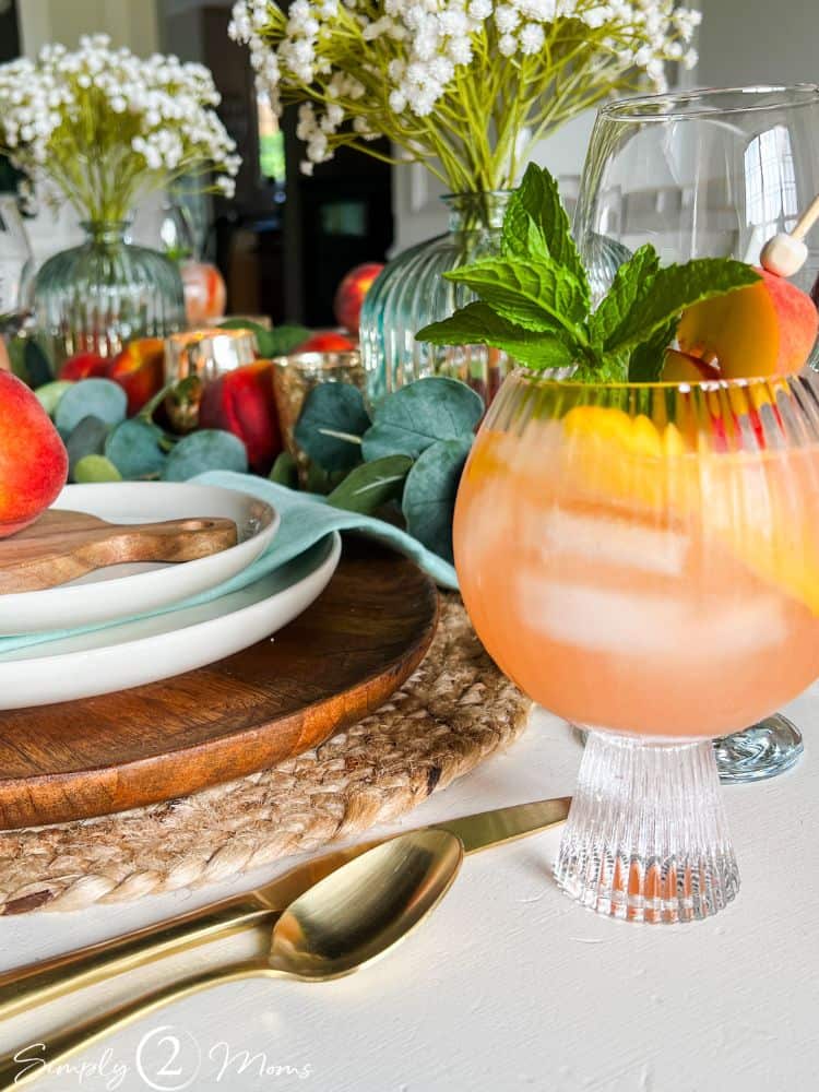 Table decorated for a peach-themed dinner party with a goblet of peach sangria.