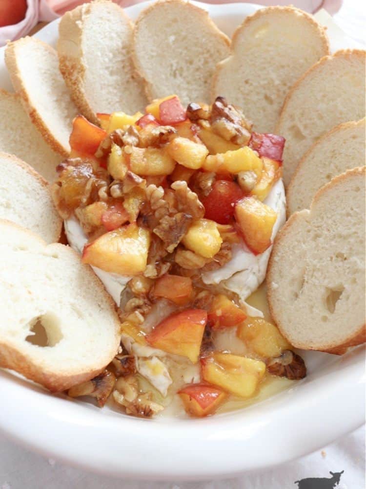 Baking dish with baked brie topped with peaches and walnuts from The Crowned Goat.