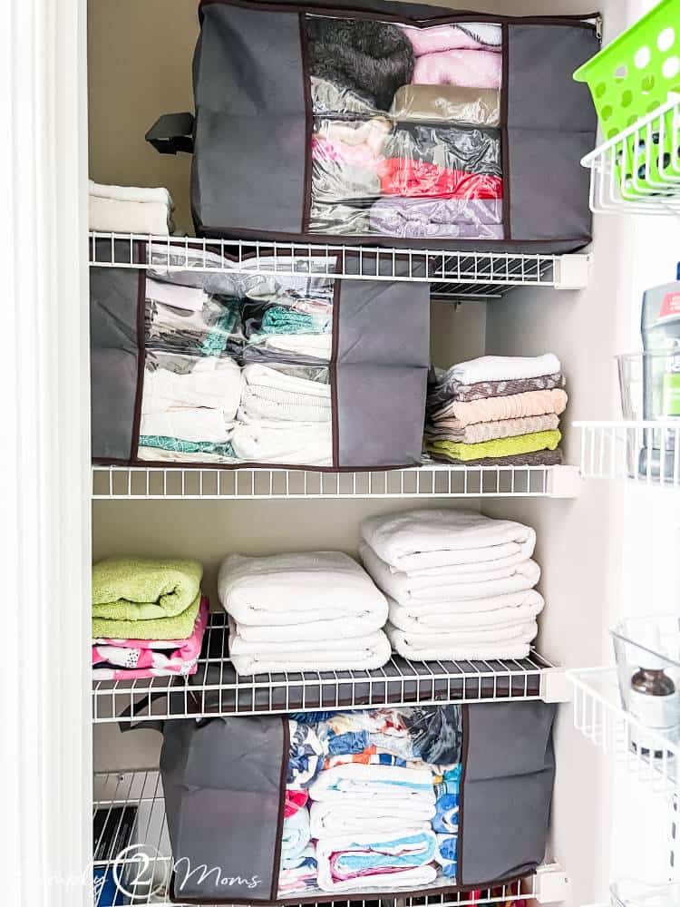 fabric storage totes in linen closet filled with sheets and blankets