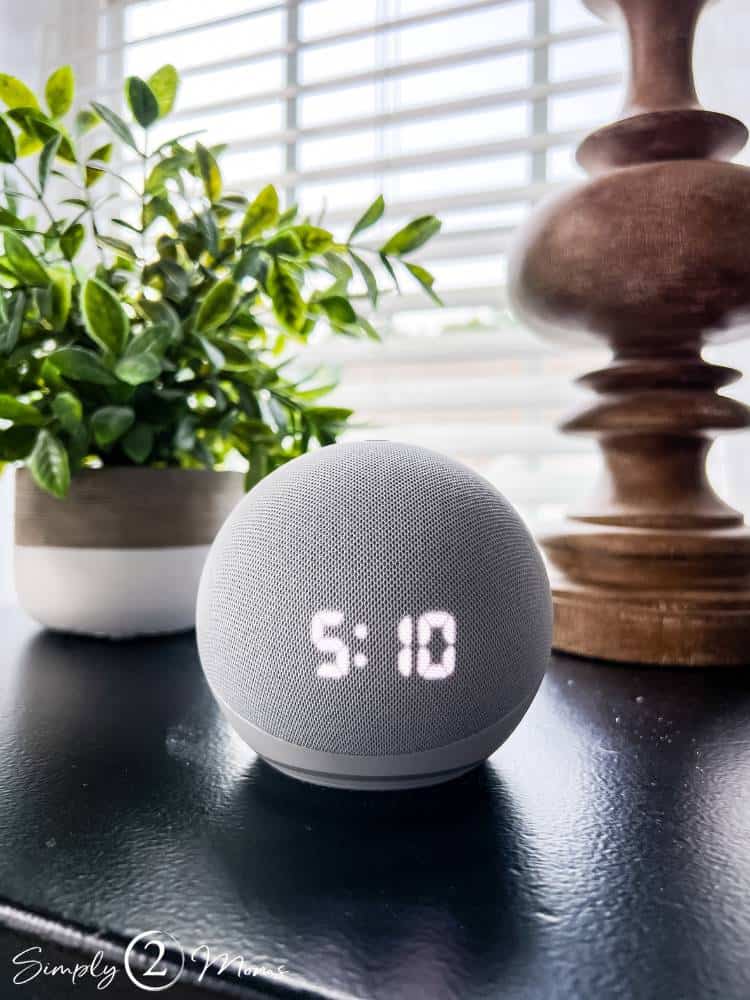 Echo dot on bedside table with faux plant and wood lamp