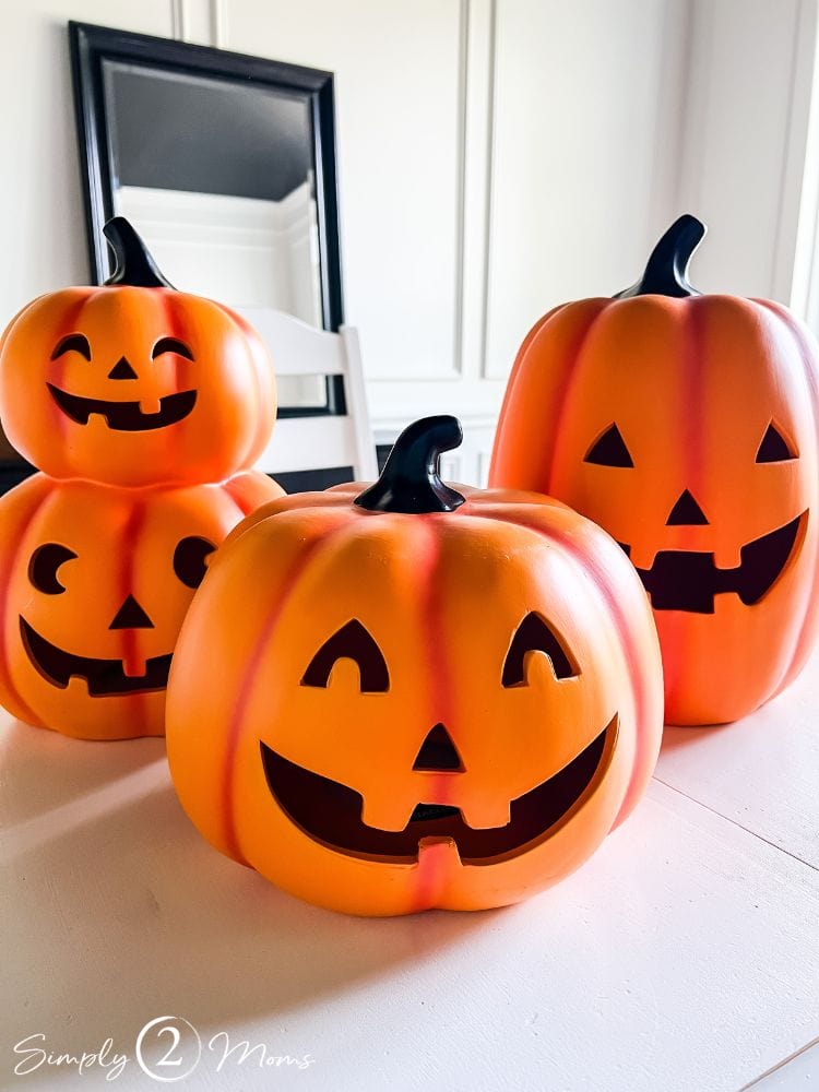 Three large orange ceramic Jack o'lanterns on a table.