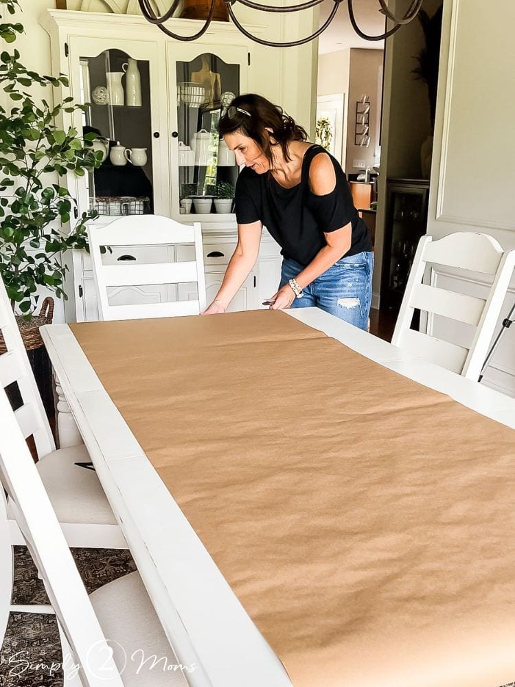 Woman putting brown postal paper on her dining table to protect it
