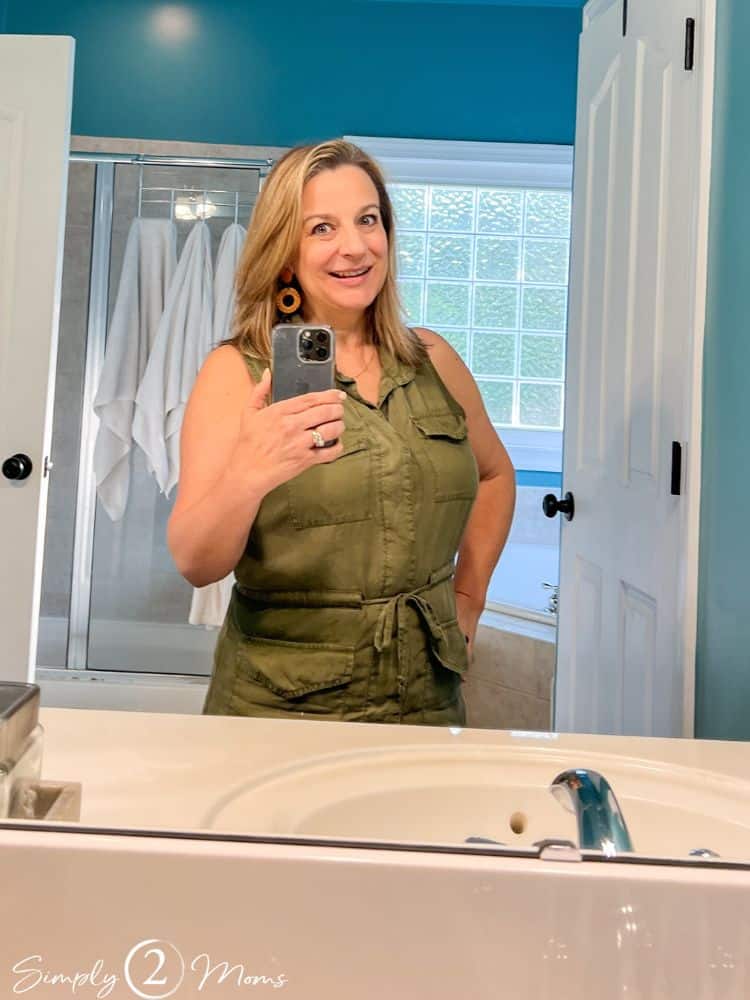 Woman in front of a bathroom mirror with ash brown colored hair with highlights after drying her air.