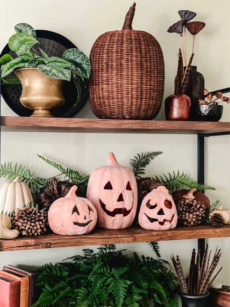 DIY pumpkins on wood shelves with greenery and pinecones