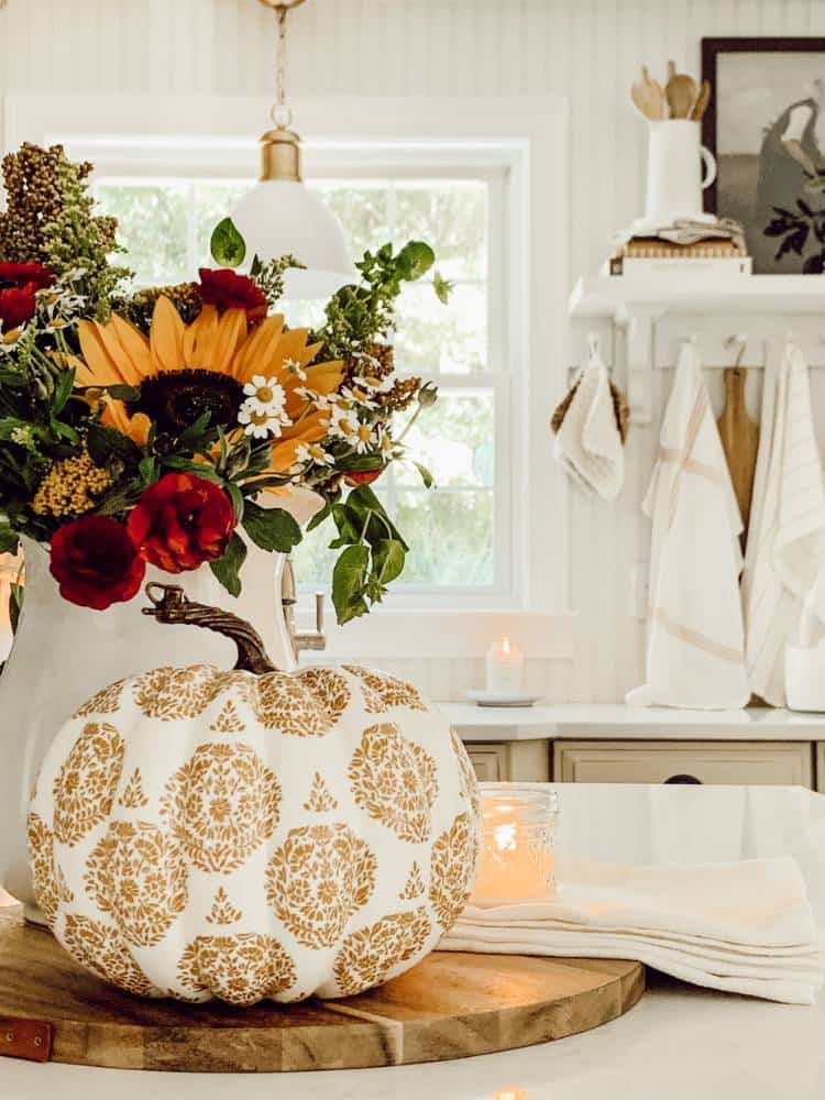 fall gold decoupage pumpkin next to fresh cut flowers in vase