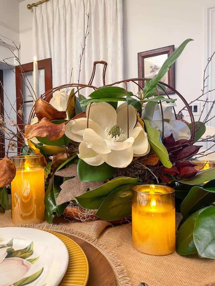 fall floral centerpiece with amber candles on dining table