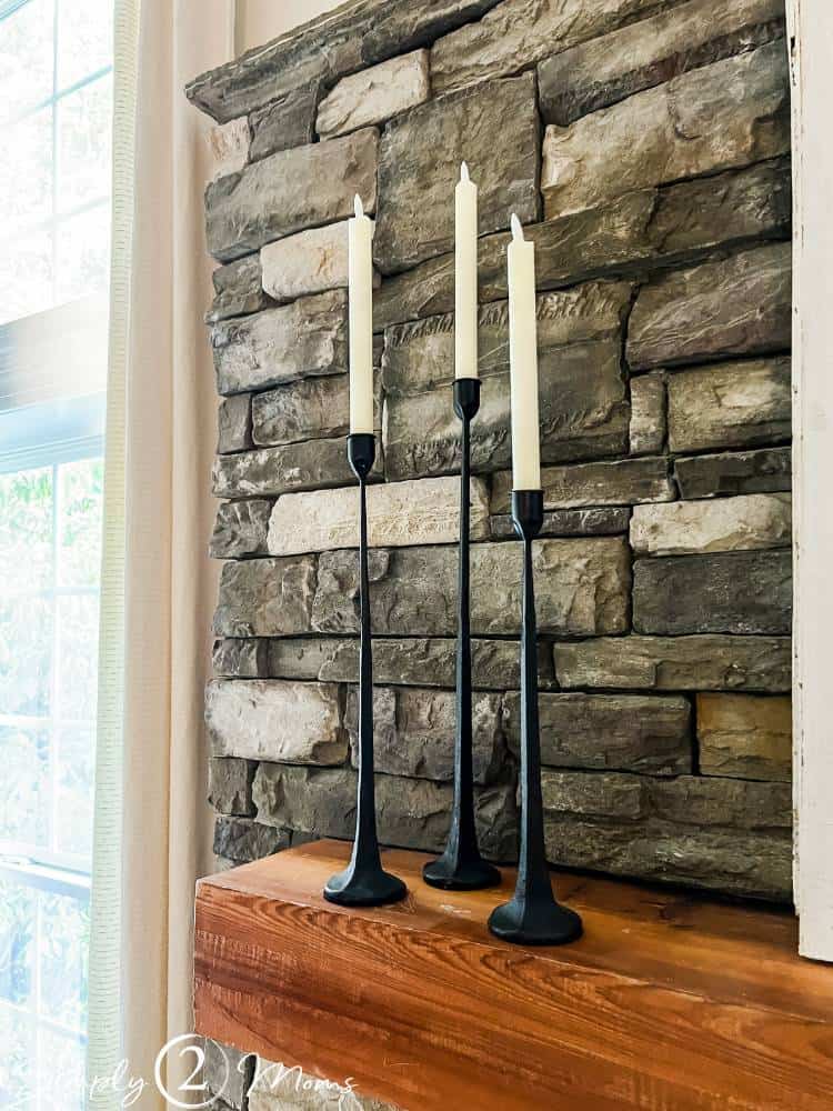 candle sticks with flameless candles on wood fireplace mantel with stone fireplace