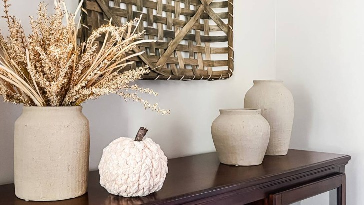 chunky yarn braided pumpkin on tabletop with neutral vases and fall faux stems
