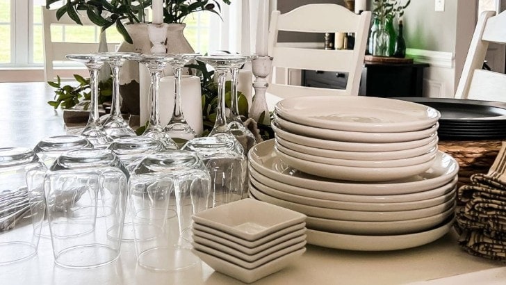 stacks of plates next to wine glasses and other table essentials