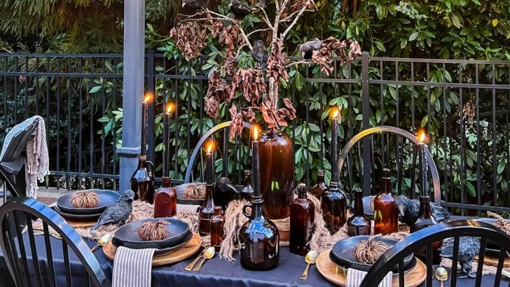 table set outside for Halloween with amber bottles and candles
