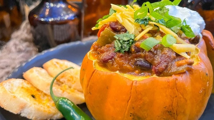 Pumpkin chili served in mini pumpkin bowls topped with shredded cheese and green onions.