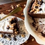 Slice of chocolate hazelnut pudding pie on a wood tray next to the full pie.