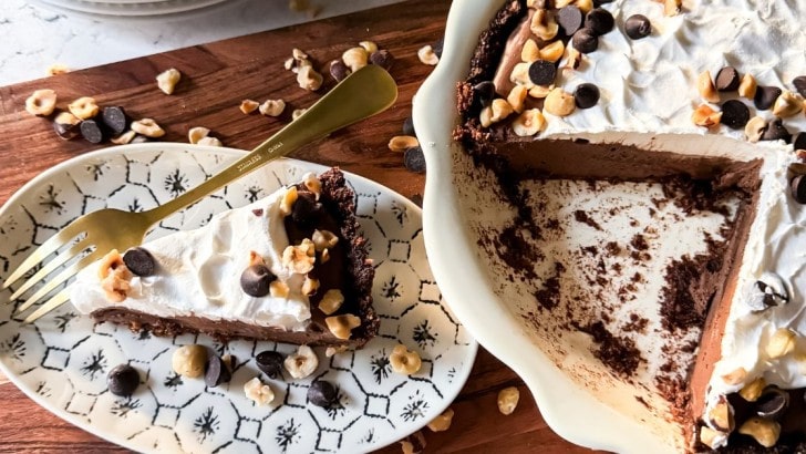 Slice of chocolate hazelnut pudding pie on a wood tray next to the full pie.