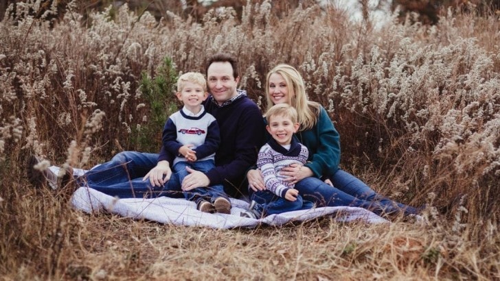 Family of four with two young boys wearing navy and teal for fall family photos.