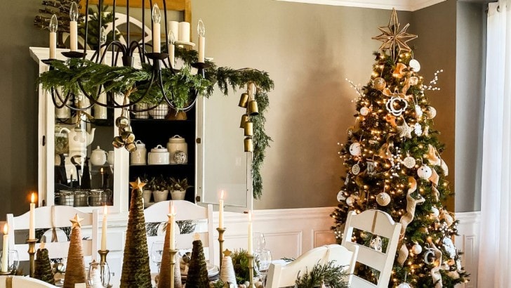 Dining room decorated for Christmas with greenery on the chandelier and a Christmas tree with neutral farmhouse decorations.