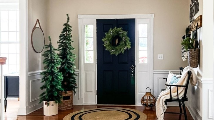inside of home by front door with bench and small Christmas trees decorating the space