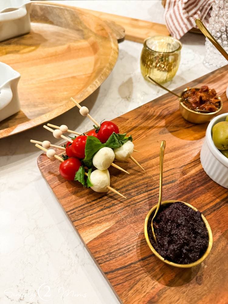 caprese appetizer on bamboo skewer on charcuterie board