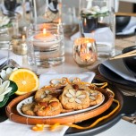 Plate of almond cookies garnished with oranges and lotus blossoms on a table set for an Asian dinner party.