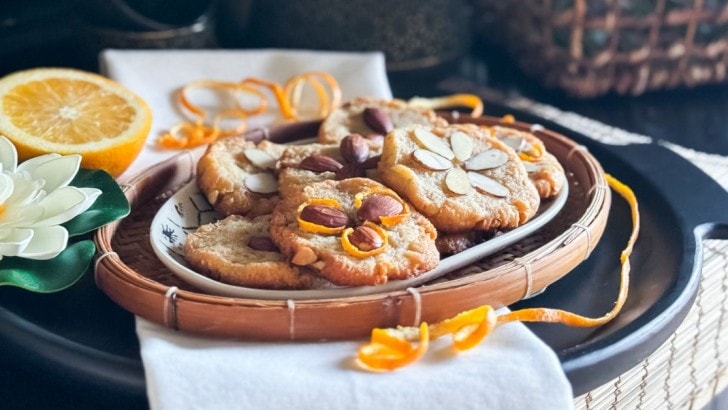 Plate of keto Chinese cookies decorated with almonds to look like flowers with orange peel curls.