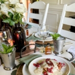 Table set for a Kentucky Derby party with white roses and mint julep cups and a plate with Kentucky Hot Brown Sandwich.