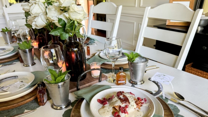 Table set for a Kentucky Derby party with white roses and mint julep cups and a plate with Kentucky Hot Brown Sandwich.