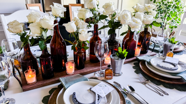 feature photo dining table styled for derby dinner party with white roses in amber bottles