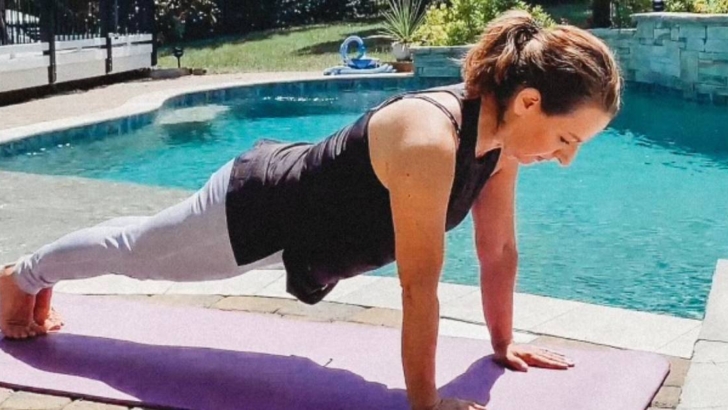 woman in yoga pose on mat beside swimming pool