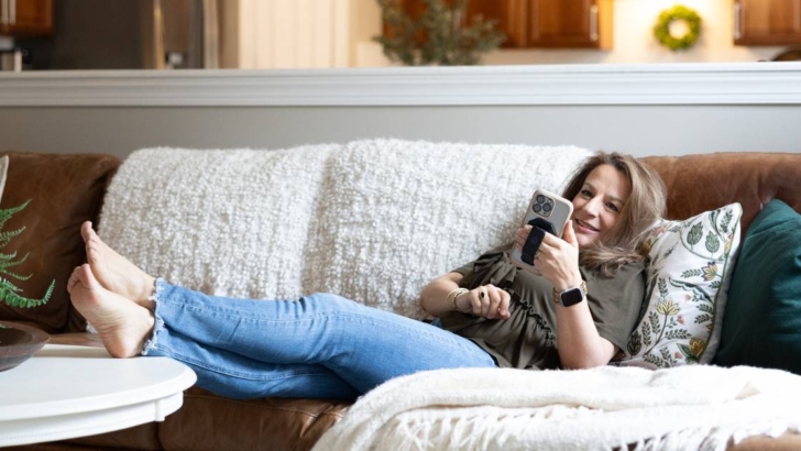 woman lounging on couch with feet up on coffee table scrolling on phone
