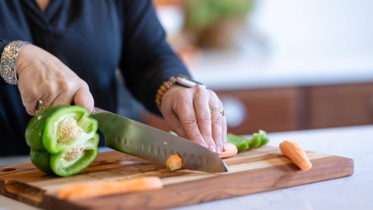 hands chopping vegetables with knife on cutting board