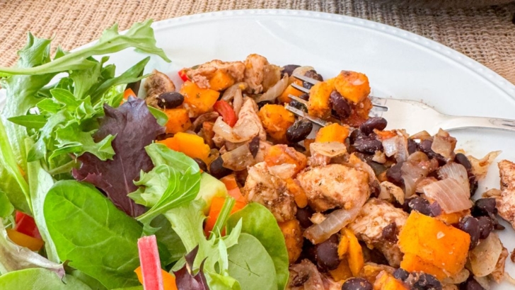 Healthy Caribbean chicken skillet meal with black beans and sweet potatoes on a dinner plate with a green salad.