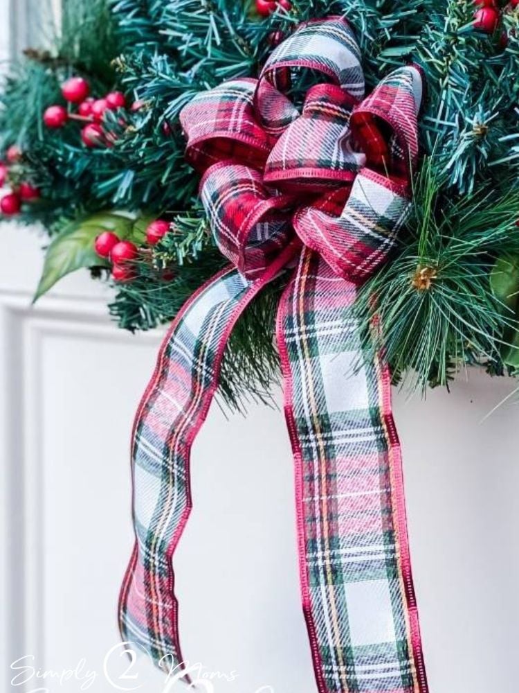 Fluffy plaid christmas bow hanging on garland with holly berries