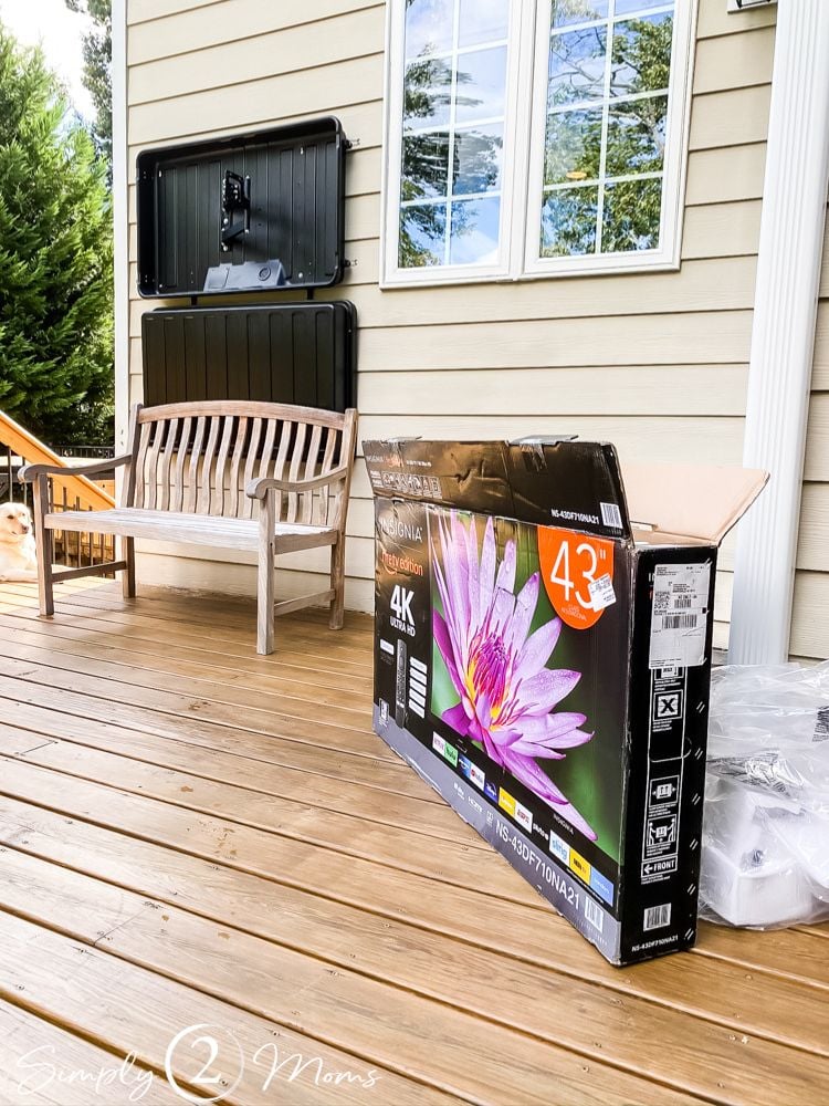 TV packaging on deck next to a mounted outdoor TV cover shell