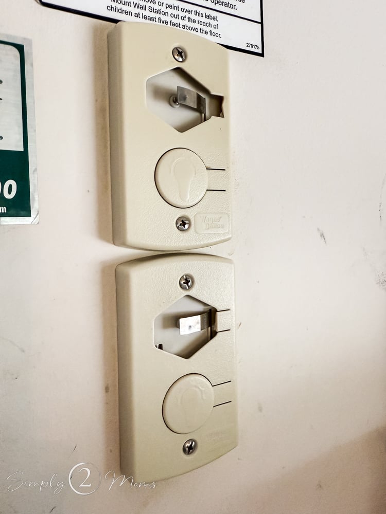 Broken garage door openers installed on a wall missing the main button.