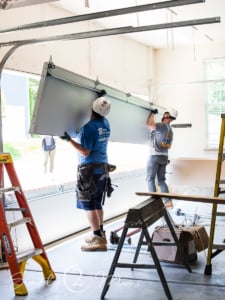 Two garage door installers lifting a panel for a 2-car garage door.