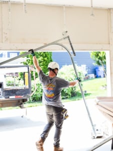 Door Systems installer carrying assembled garage door track.