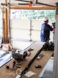 Installer wearing a hard hat removing old garage door panels.