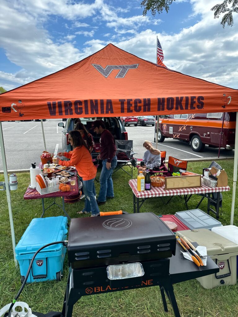 Virginia Tech Hokies tailgate setup with grill, coolers, and food tables, showing the festive atmosphere of a family game day gathering.