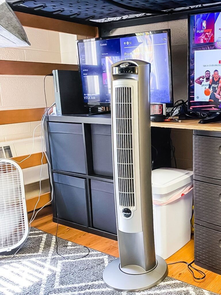 Dorm room with tower fan, desk setup, and storage organizers